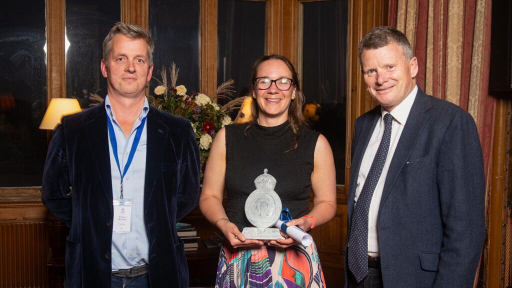 Photograph of three people holding an award smiling to camera